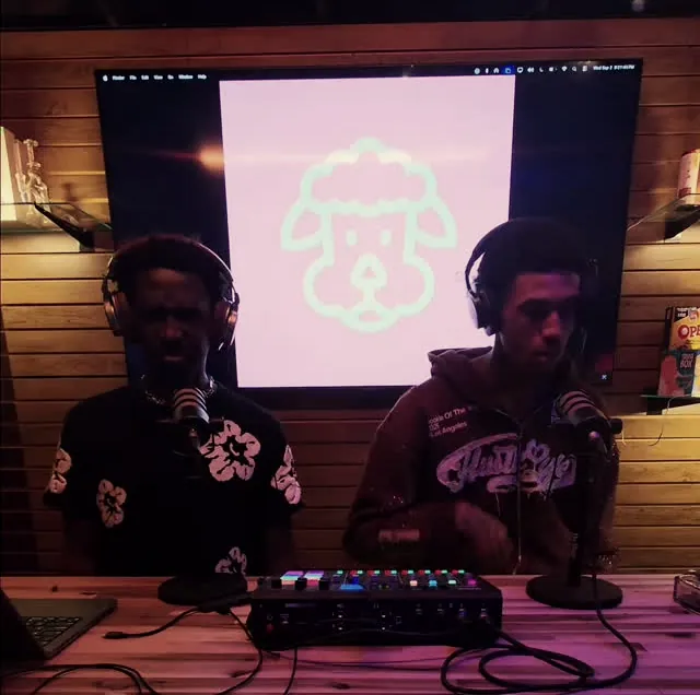 Two hosts recording at the Black Diamond DJ and podcast booth under pink light
