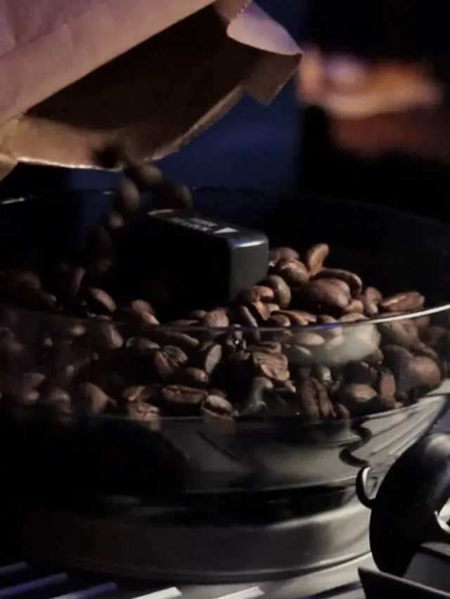 Coffee beans pouring into a grinder hopper