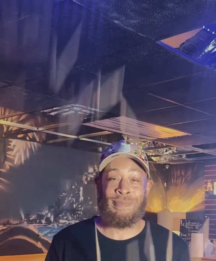 A host in a Black Diamond tee in the lounge, amber and blue light behind him