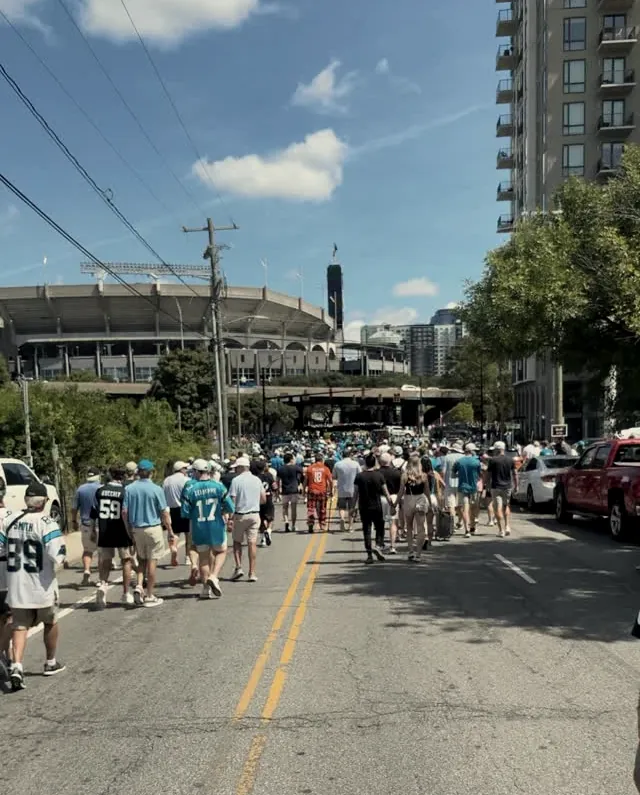Panthers fans walking toward the stadium on a sunny game day